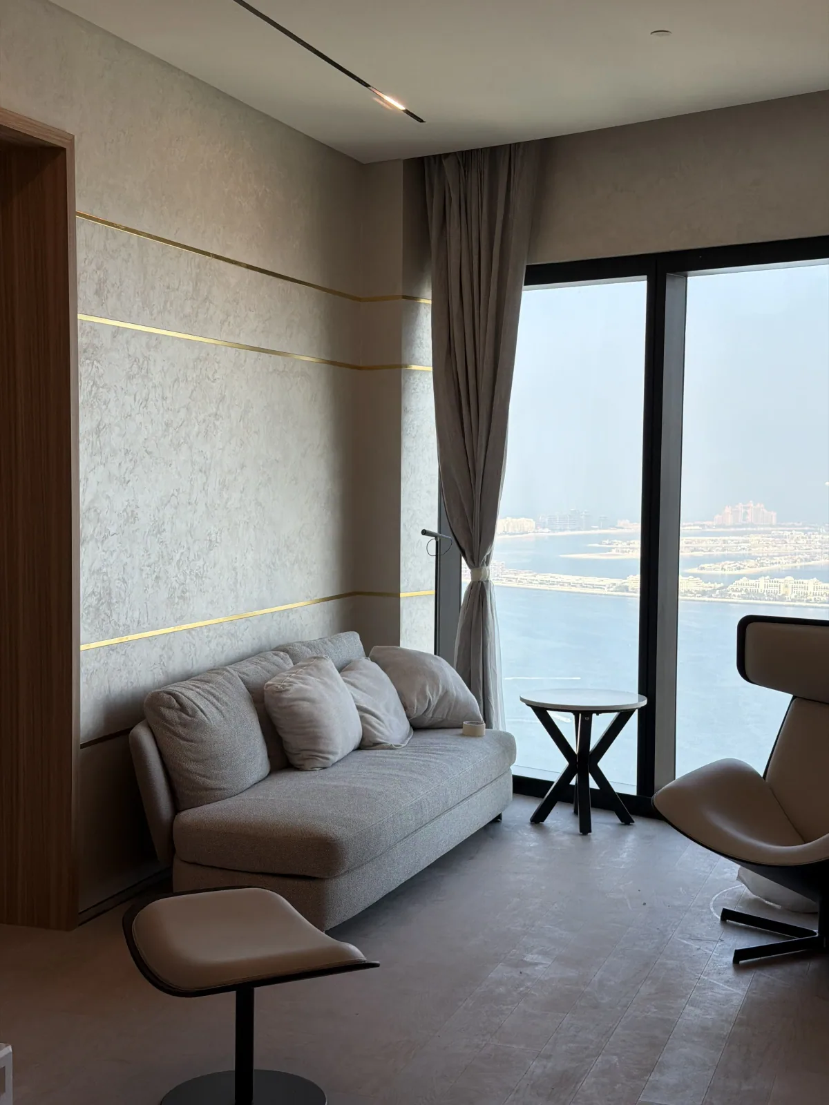 Textured microcement feature wall with brass inlay lines beside a sea view