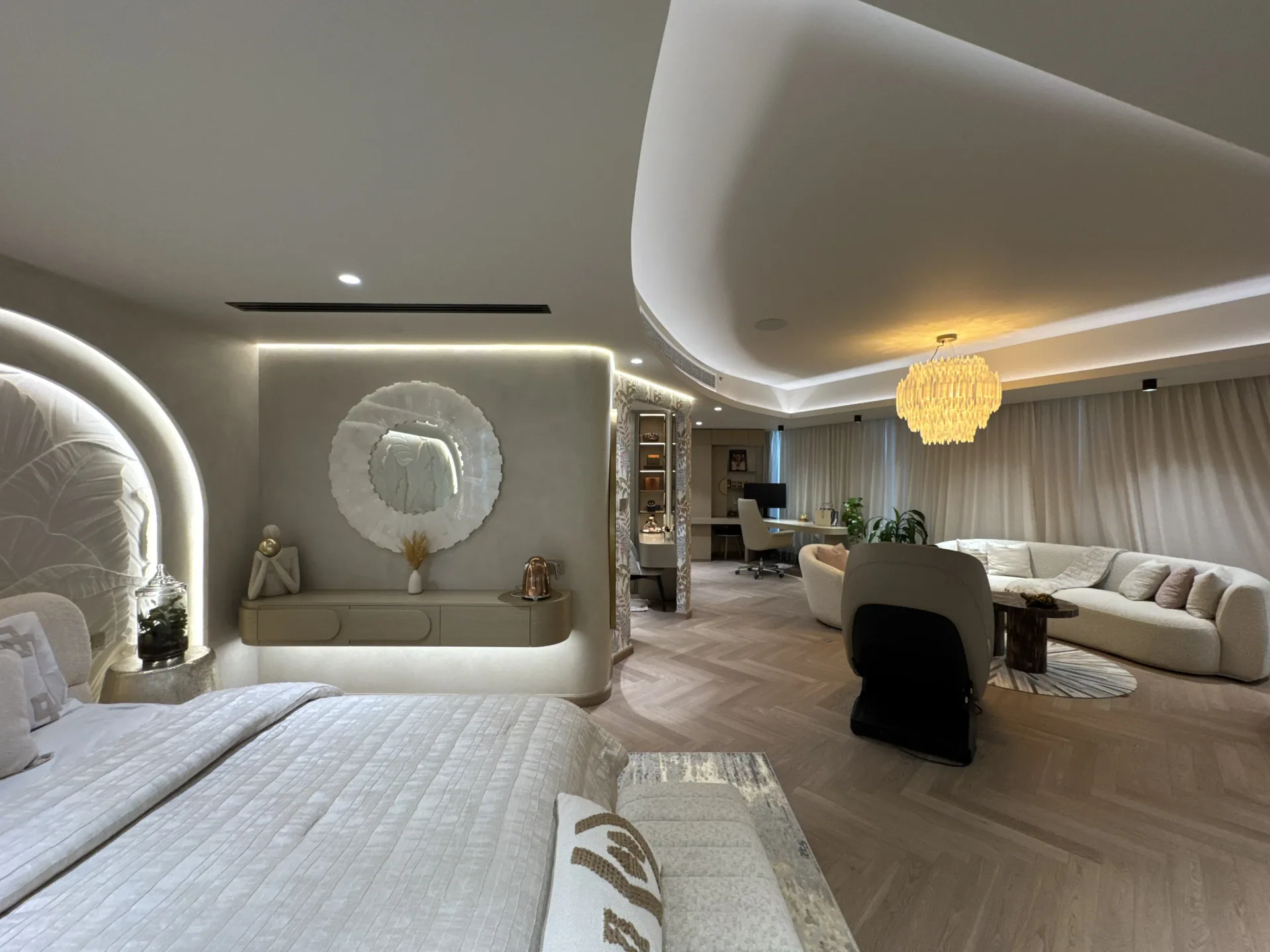 Master bedroom suite wrapped in curved microcement walls with a feature chandelier
