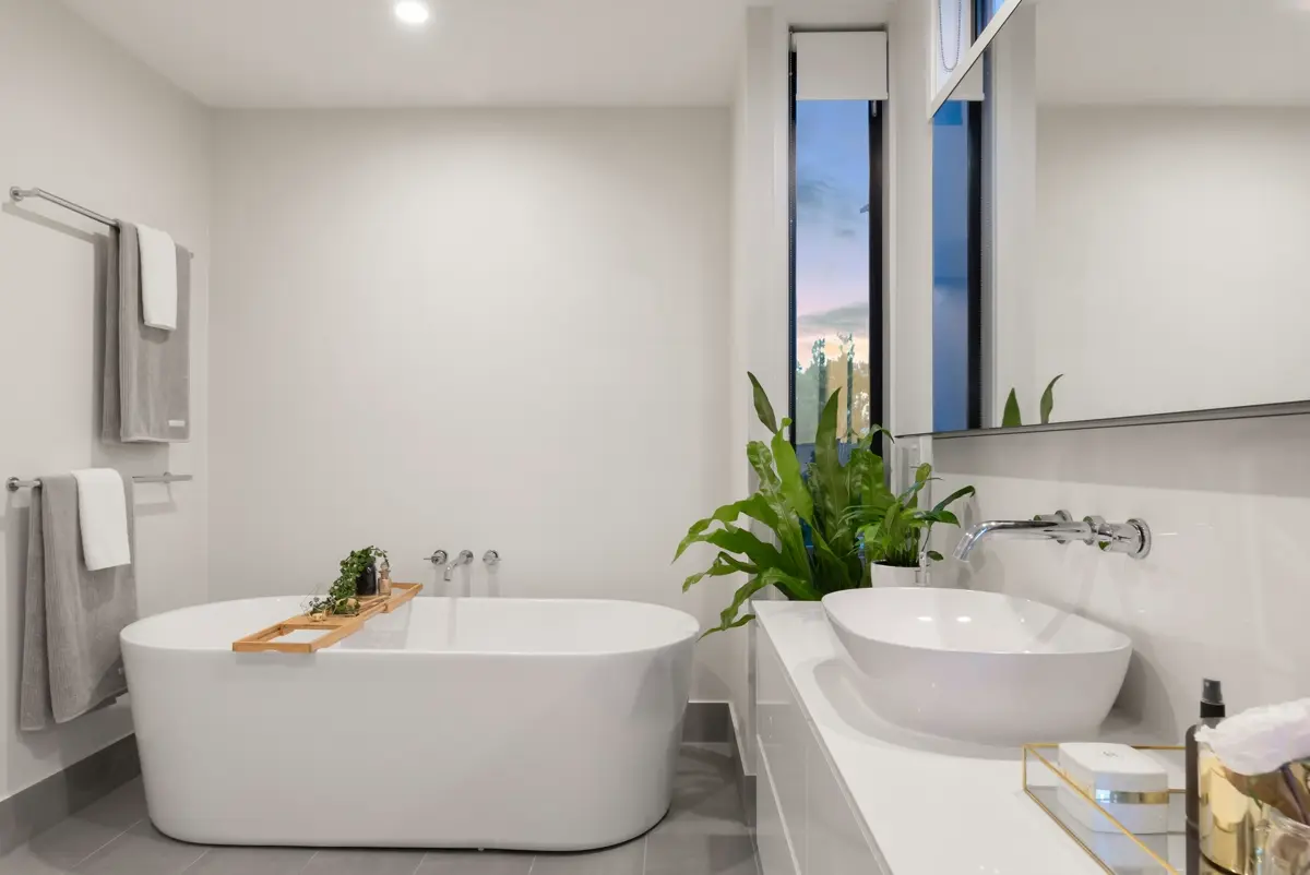 Bright bathroom with a freestanding bath, pale walls and a long vanity.