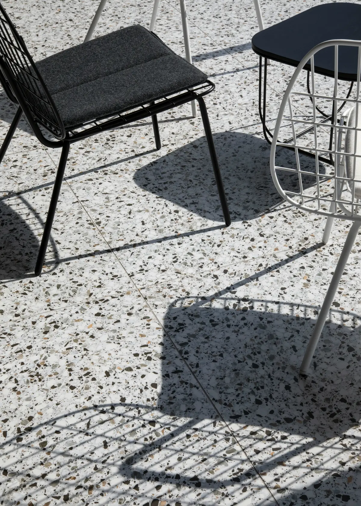 White terrazzo floor with dark aggregate beneath outdoor seating.
